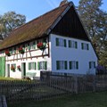 Staudenhaus mit Strohdach, grünen Fensterläden, Blumenkästen