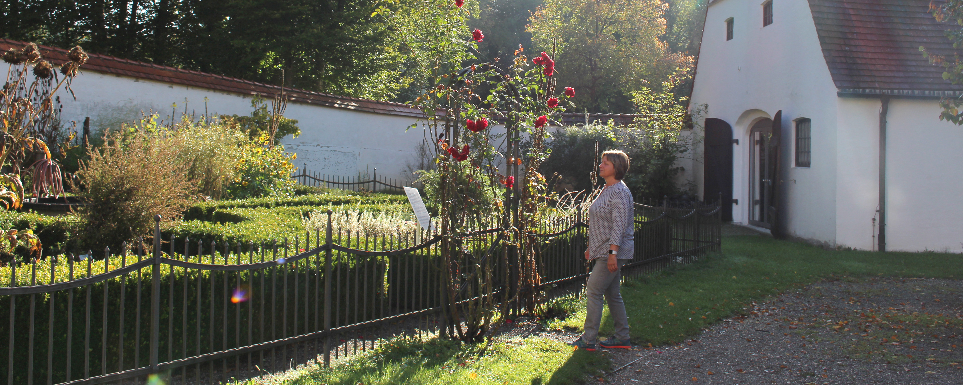 Besucherin am Tor mit Rosenbogen