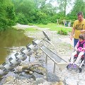 Vater, Mutter und Kind mit Rollstuhl am Bachlauf