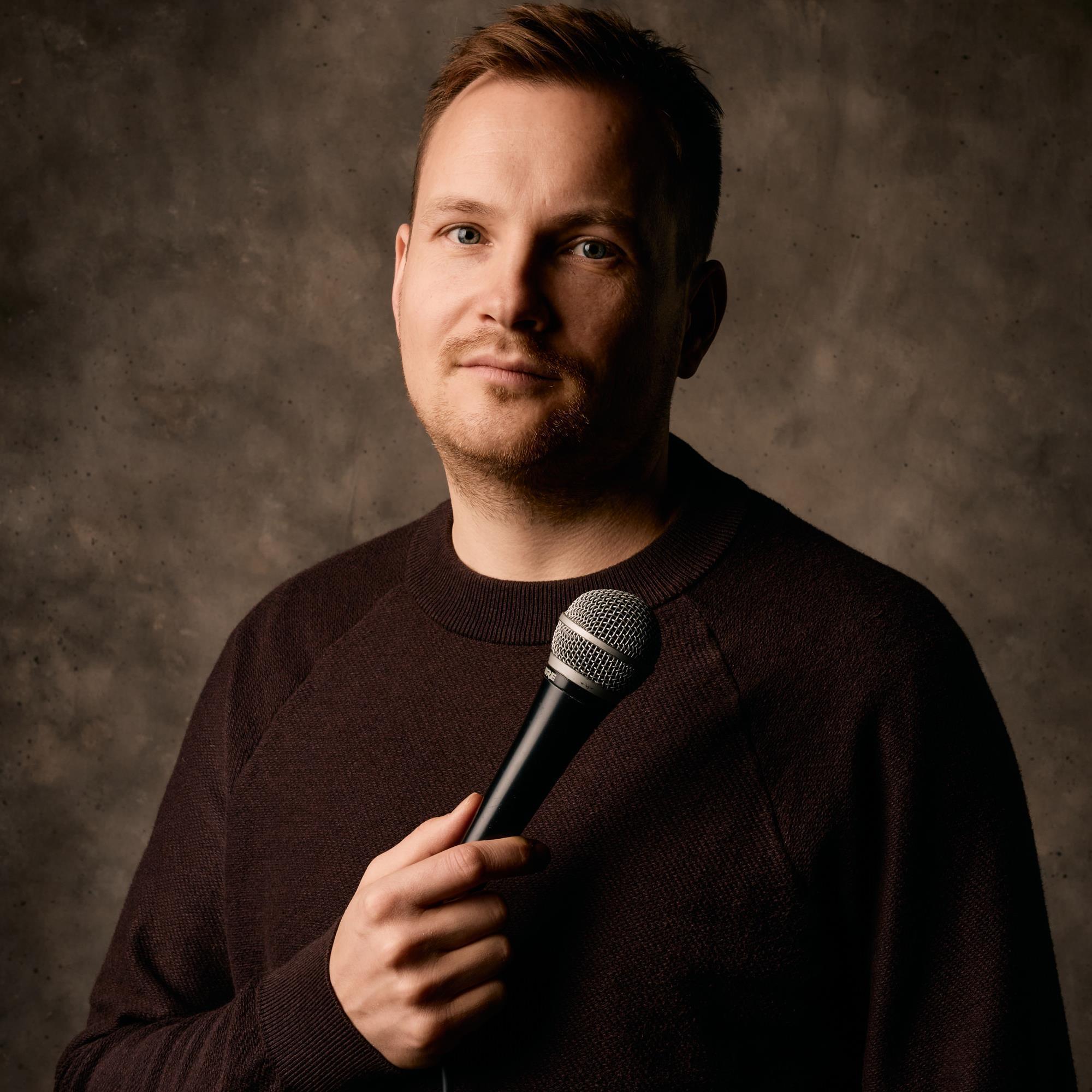 Portrait Jakob Schwertfeger mit Micro vor dunklem Hintergrund