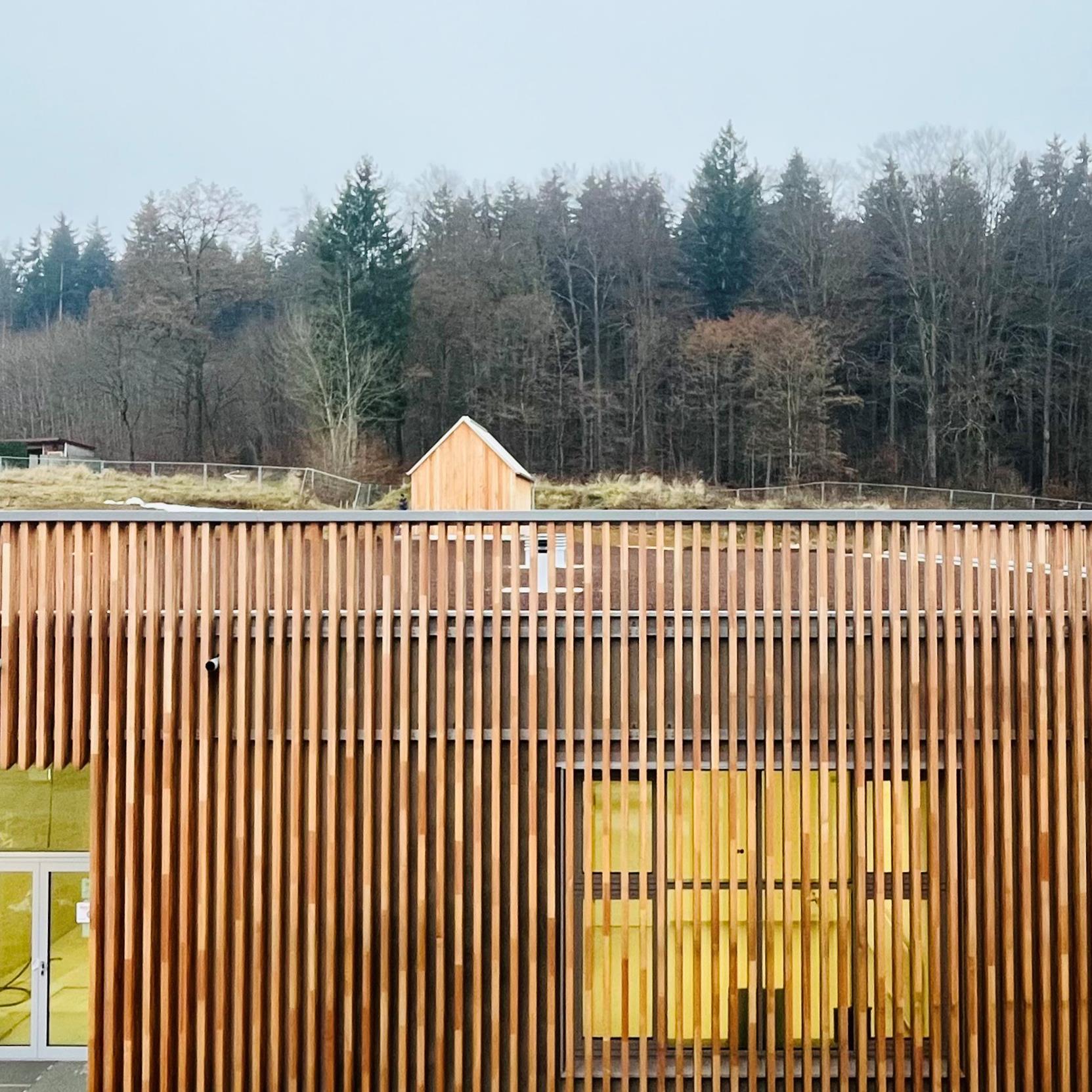 Holzverkleidete Fassade mit Bäumen im Hintergrund