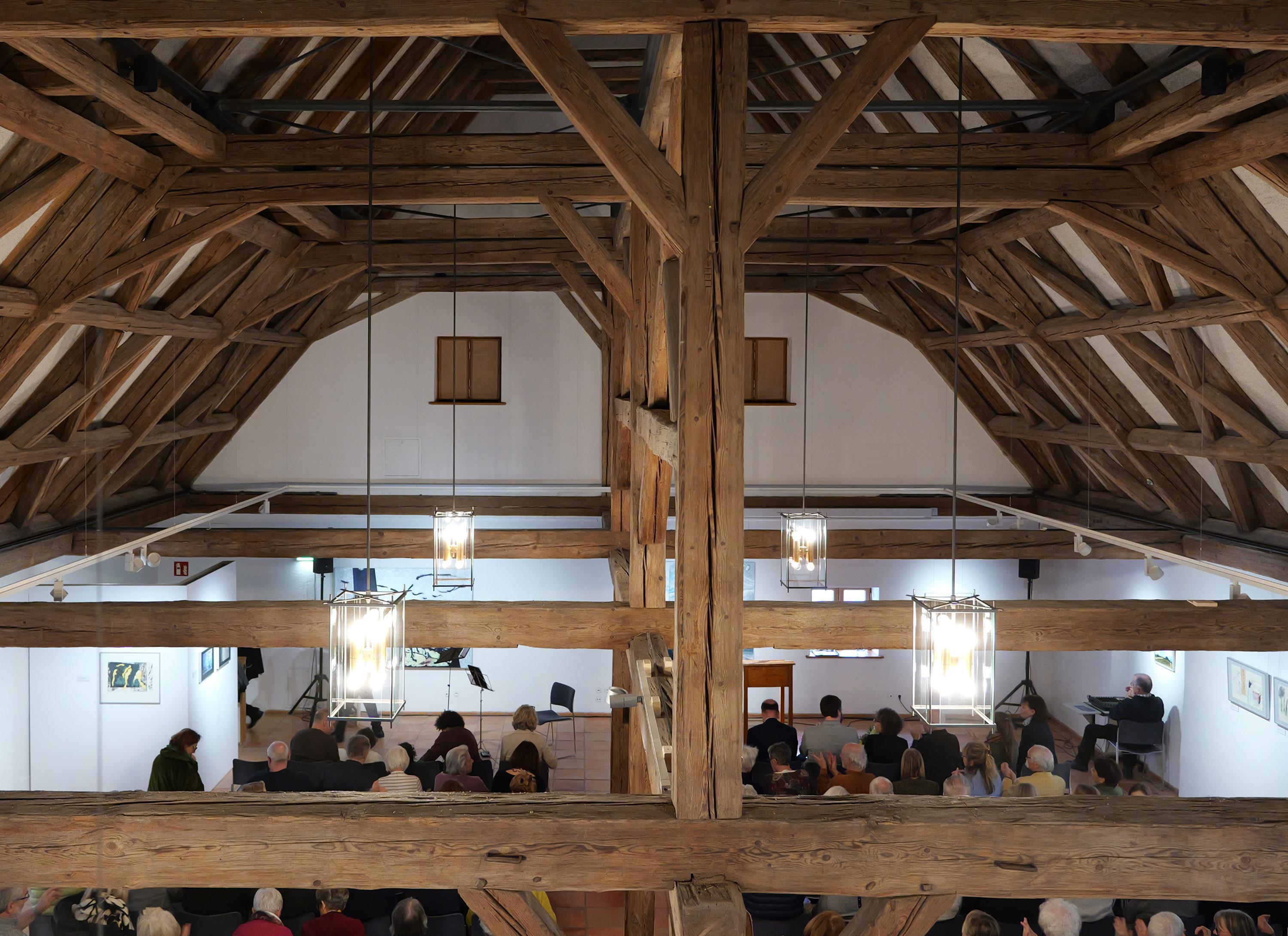 Blick in den historischen Dachstuhl auf Besucher im Obergeschoss